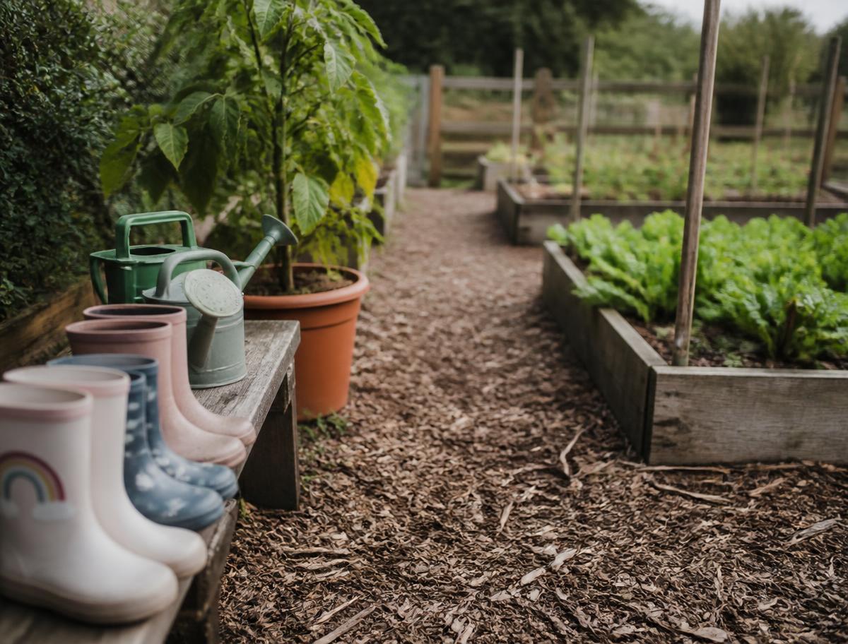 Wellies lined up beside watering cans in the nursery garden